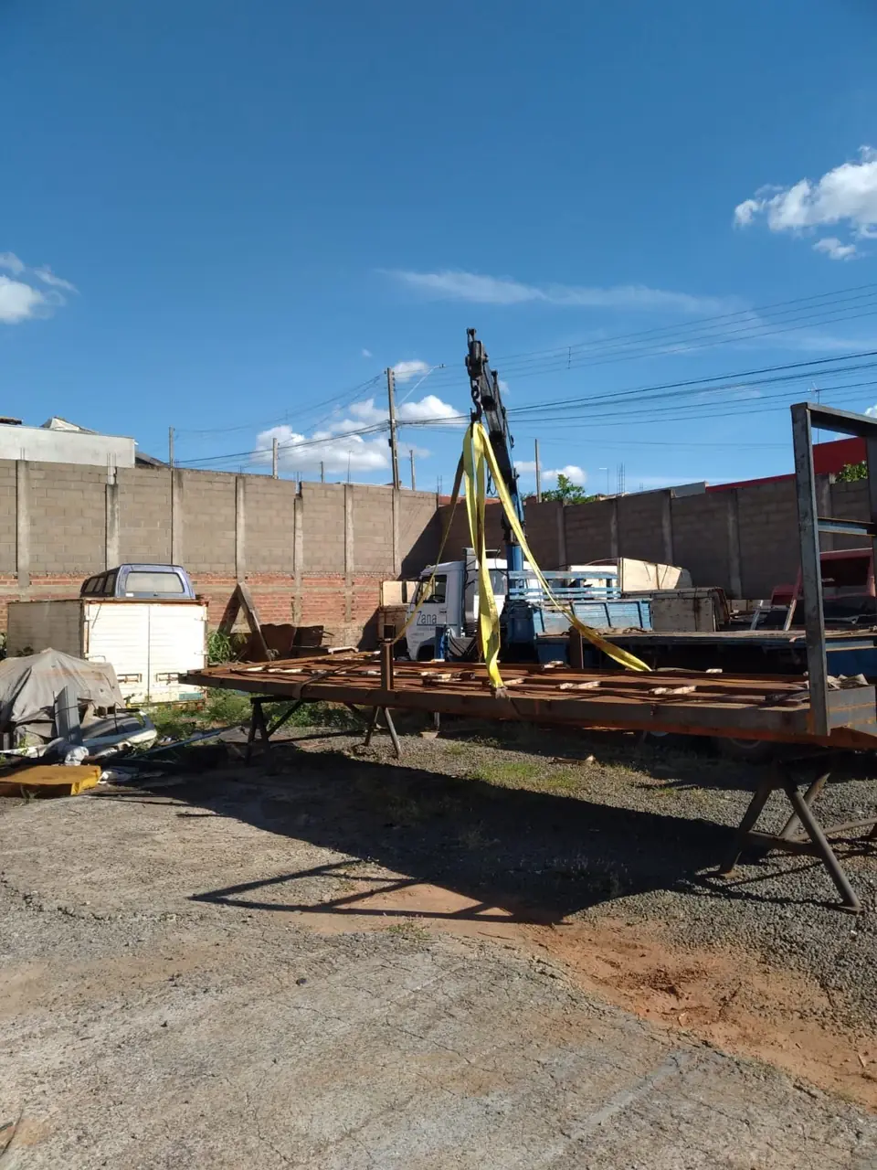 Caminhão munck da Zana içando estrutura metálica com cintas em pátio