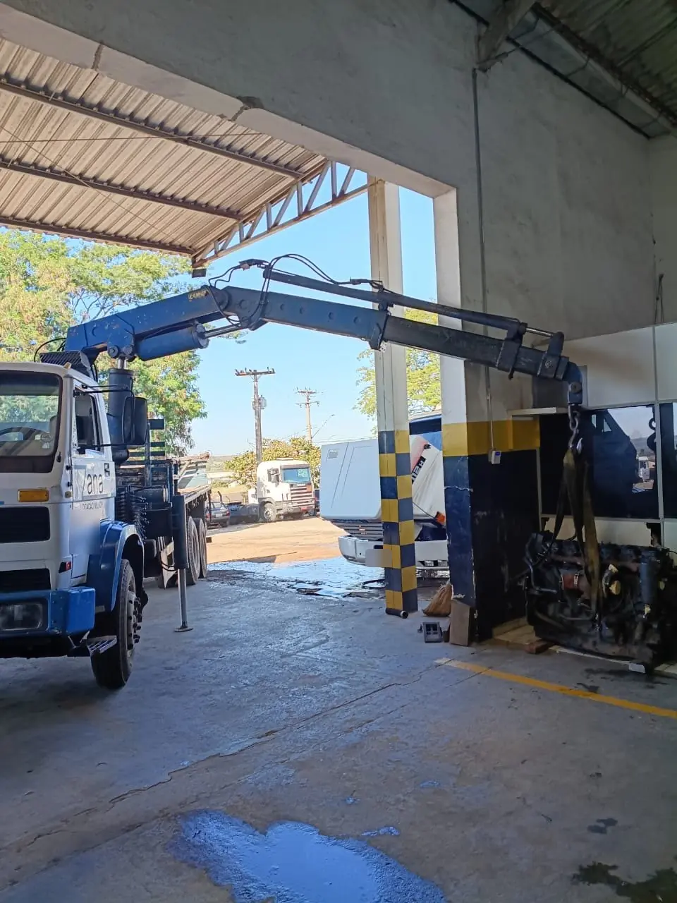 Caminhão munck da Zana removendo motor de caminhão dentro de oficina