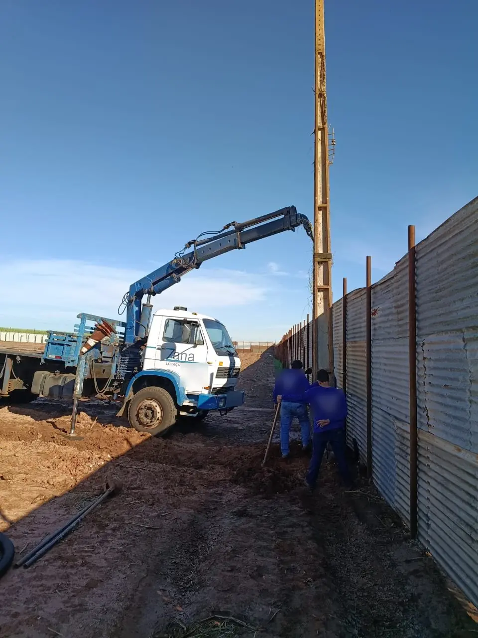 Caminhão munck da Zana instalando poste em área rural